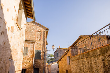 A picturesque view of a traditional stone village with rustic buildings and iron railings, illuminated by the warm sunlight under a clear blue sky, showcasing the timeless charm of historic