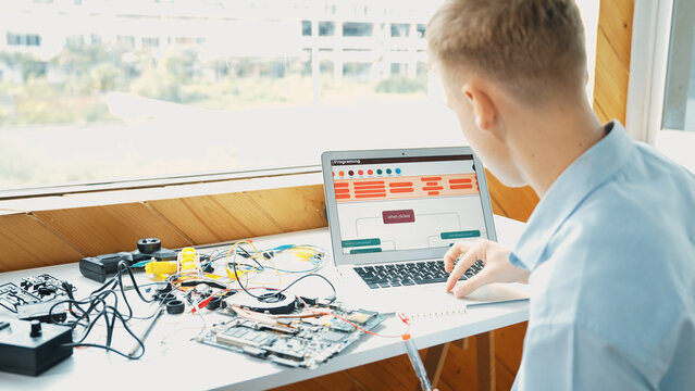 Caucasian student looking at laptop screen while coding engineering prompt or programing system. Back view of smart teenager working by using computer and electronic tool at STEM class. Edification.