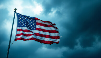 American flag waving against a backdrop of dark, cloudy skies. The flag shows signs of wear with frayed edges, prominently displaying red and white stripes along with blue field featuring white star