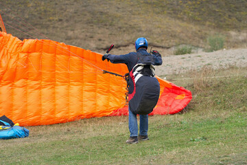 Paraglider landing. The pilot put the canopy on the ground and untangles the slings.