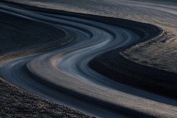 winding road through a dark landscape, aerial view