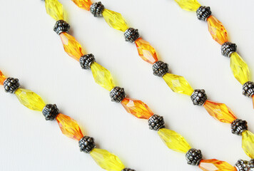 Elegant yellow and orange beaded strands with metallic spacers on a white background. Stylish...