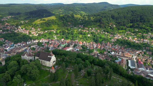 Aerial view of historic centre of Sighisoara, Romania. It is a popular tourist destination for its well-preserved old town, which is listed by UNESCO as a World Heritage Site. Drone Backwards.