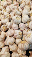 Garlic close up in supermarket. Lots of garlic in plastic green box on market stall. Garlic in green plastic box at farmers market. Garlic for sale in store. Display of fresh produce for sale