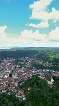 Historic centre of Sighisoara, Romania, aerial view. It is a popular tourist destination for its well-preserved old town, which is listed by UNESCO as a World Heritage Site. Drone circling. Vertical 