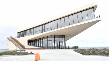 Modern, sloping beige building with glass facade and outdoor deck.