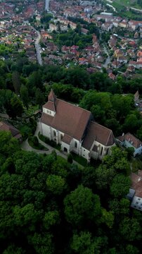 Historic centre of Sighisoara, Romania, aerial view. It is a popular tourist destination for its well-preserved old town, which is listed by UNESCO as a World Heritage Site. Drone circling. Vertical 