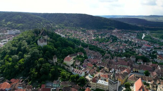 Aerial perspective of historic centre of Sighisoara, Romania. It is a popular tourist destination for its well-preserved old town, which is listed by UNESCO as a World Heritage Site. Drone circling.