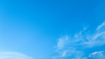 A calm and clear summer sky with gentle, wispy clouds moving across, offering a refreshing backdrop.