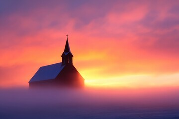 Obraz premium a small church stands silhouetted against a vibrant sunrise, with fog rolling across a snowy field.
