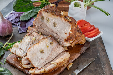 Baked piece of pork - ham. Delicious spicy meat. Spicy meat baked with garlic and chili peppers. A piece of baked meat with spices and vegetables on the table