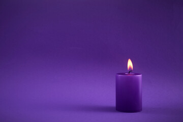 Purple Candle. A single purple candle burning with a soft flame