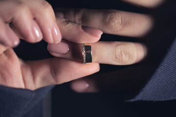 A woman removes her wedding ring from finger.
