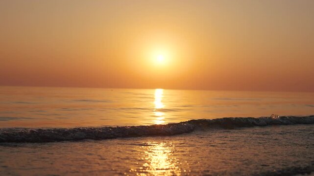 4K Slow motion shot of a beautiful sunset at Mandvi Beach in Kutch, Gujarat, India. Sea waves and entire sea becomes golden in colour during the sunset. Orange colored sea. Natural sea background.