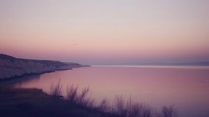 Obraz premium Serene coastal sunset over calm waters and cliffs