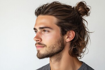 Portrait of a young caucasian male model with trendy long hair and beard, looking away from the camera