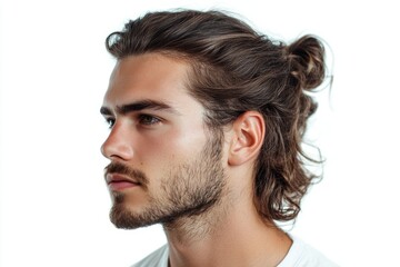 Obraz premium Portrait of a confident young man with long brown hair tied in a bun and a beard, looking away against a gray background