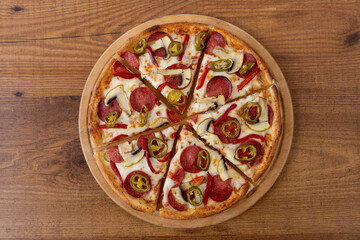 Pizza with salami, pepper and mushrooms on a wooden table, Italian pizza