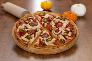 Pizza with salami, pepper and mushrooms on a wooden table, Italian pizza