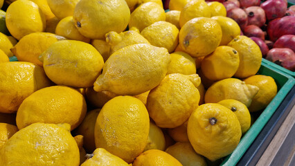 Sale of lemons in a supermarket. Citrus fruits in plastic boxes, close-up. Lemons in a store. Ripe, juicy, bright yellow lemons. A pile of lemons for sale at the market