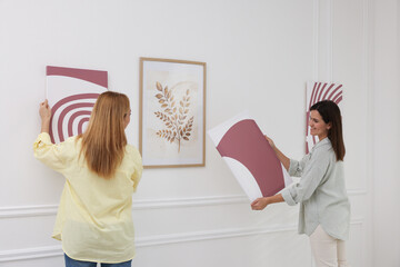 Women hanging paintings on wall in art gallery