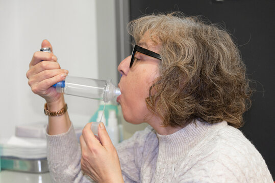 Mature woman using inhalation device for respiratory treatment