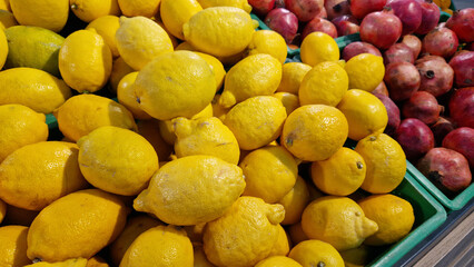 Sale of lemons in a supermarket. Citrus fruits in plastic boxes, close-up. Lemons in a store. Ripe, juicy, bright yellow lemons. A pile of lemons for sale at the market