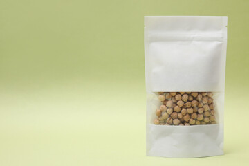 Paper pouch bag with chickpeas on light green background. Space for text