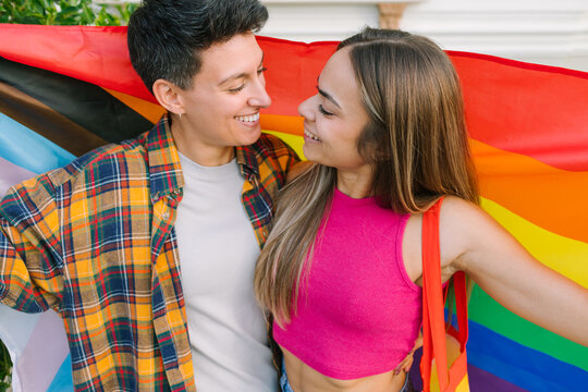 Lesbian Couple Smiling and Embracing with Pride and Trans Flags