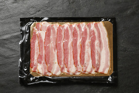 Pack of sliced bacon on black table, top view - Powered by Adobe