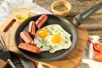 Tasty fried eggs with cut sausages served on wooden table, closeup