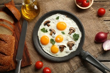 Tasty fried eggs with mushrooms and parsley served on wooden table, flat lay