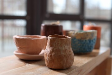 Beautiful pottery on wooden shelf indoors, closeup