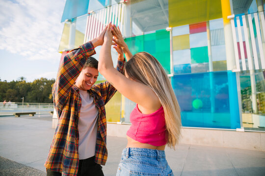 Joyful lesbian couple dancing outdoors in colorful setting