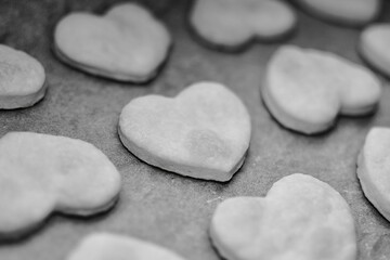 Homemade heart shape cookies cooling on baking paper. Cooking Valentines biscuits. Baking handmade love day treats. Heart biscuits in a row. black and white.