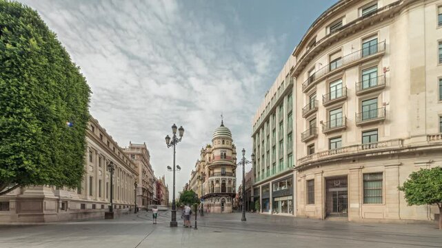 Pedestrians walking along Avda. de la Constitucion, major avenue in Casco Antiguo district of Seville, Spain. Timelapse hyperlapse with Edificio de la Adriatica, historical buildings and passing trams