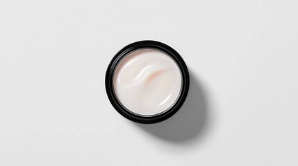 Creamy moisturizer in sleek black jar on white background
