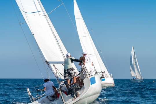 Sailors maneuvering sailboats during regatta on sunny day