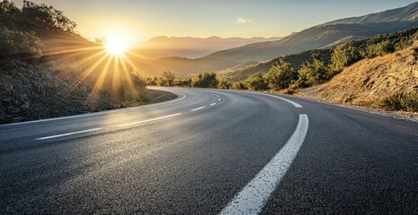 Naklejka premium Asphalt Road Winding Through Majestic Mountains at Sunset