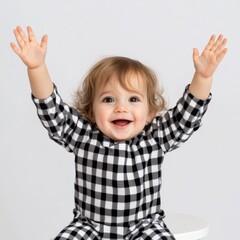 happy baby in black and white checkered pajamas with hands up