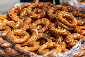 A large pile of golden-brown simits, traditional Turkish bagels, fills a clear plastic bag. The sesame-seeded rings are freshly baked, appealing and delicious-looking. Perfect for food blogs