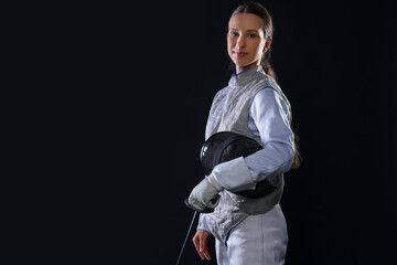 Fencer with epee on black background, space for text