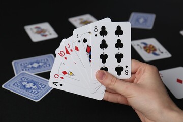 Woman with playing cards at black table, closeup