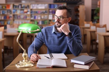 Handsome man with books at desk in library