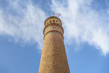 Minaret with brick patterns against a blue sky. This is the only minaret of the main mosque (Jameh...