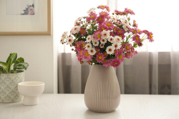 Beautiful flowers in vase and decor on white wooden table at home