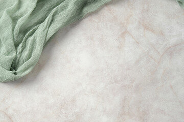 Light green gauze fabric on a textured beige marble background. Flat lay, top view