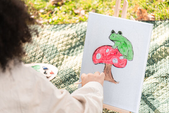 Outdoor painting of a frog on a mushroom in nature setting