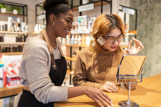Cosmetics store employee assisting customer with makeup