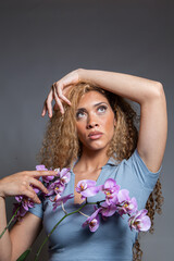 Latin woman in bluish outfit, elegant fashion portrait in studio with textured gray background and...